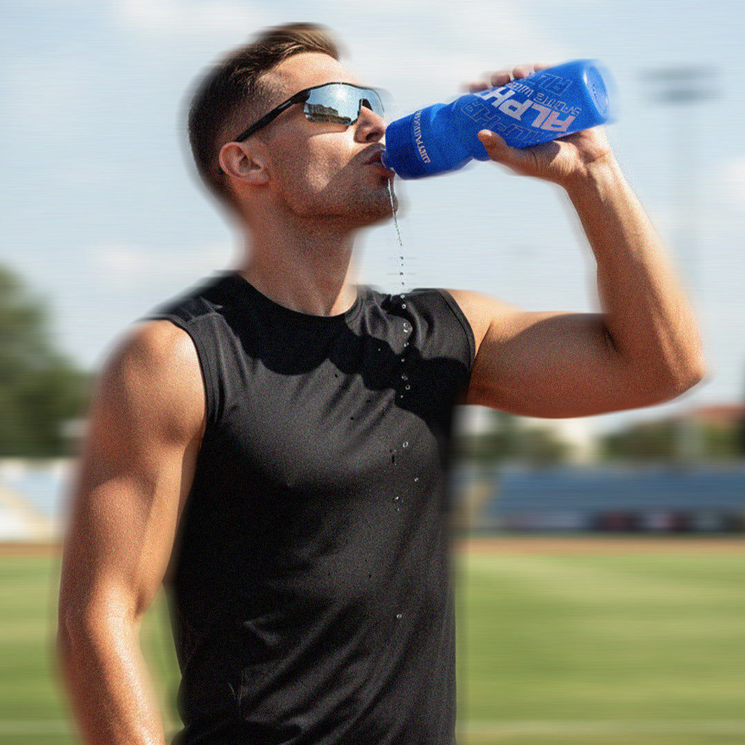 Man drinking from a blue water bottle on a track field
