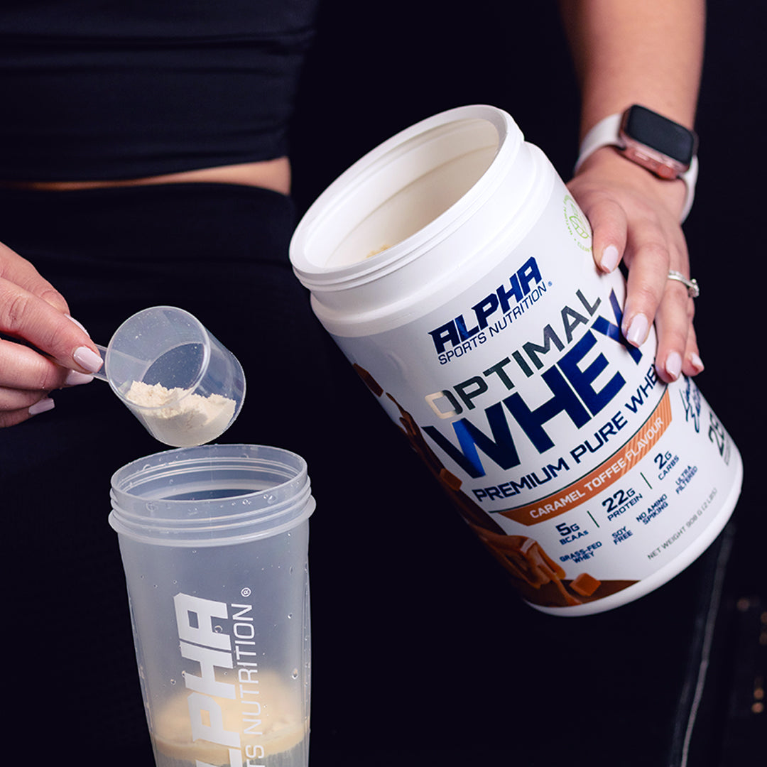 Person measuring Alpha Sports Nutrition Optimal Whey protein powder into a shaker.