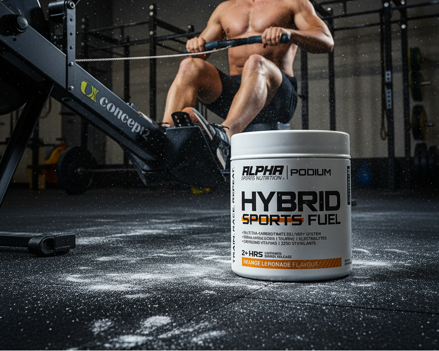 Man using a rowing machine with a container of Alpha sports nutrition Hybrid Sports Fuel in the foreground.