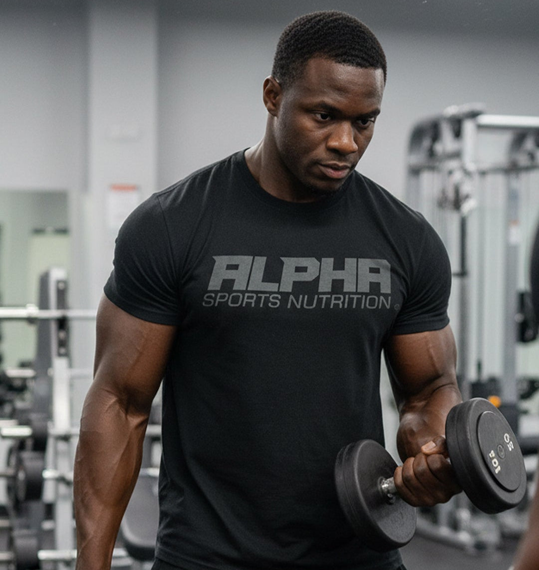 Man lifting dumbbells wearing an 'Alpha Sports Nutrition' t-shirt in a gym.